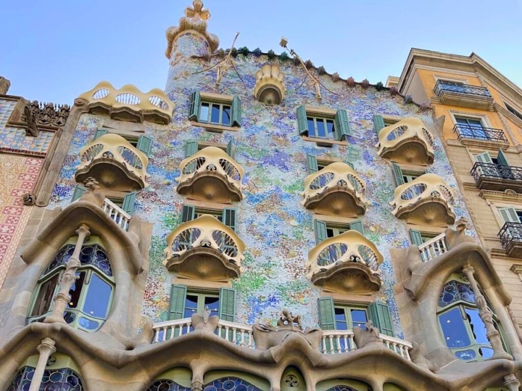 Close-up of Casa Batlló in Barcelona, featuring Gaudí's colorful mosaic facade, curved balconies resembling skulls, and green window shutters