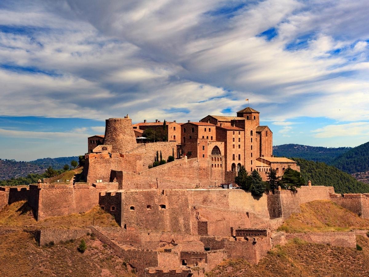 Medieval stone fortress of Castell de Cardona in Catalonia, Spain, featuring fortified walls, historic towers, and Romanesque buildings on a hill overlooking the countryside
