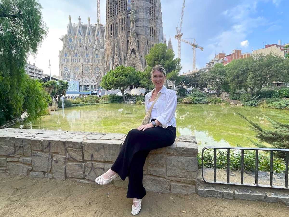 Me sitting in front of a pond with La Sagrada Familia in the background