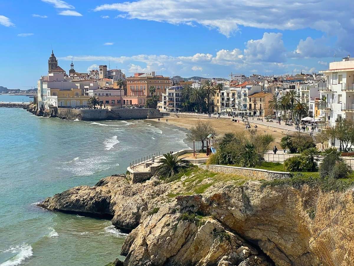 Waterfront promenade lined with palm trees and pastel-colored buildings in the seaside town of Sitges