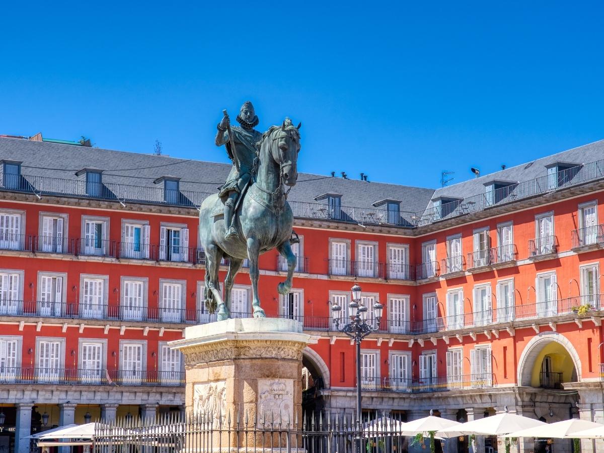 Plaza Mayor in Madrid Spain with a horse statue surrounded by red historic buildings