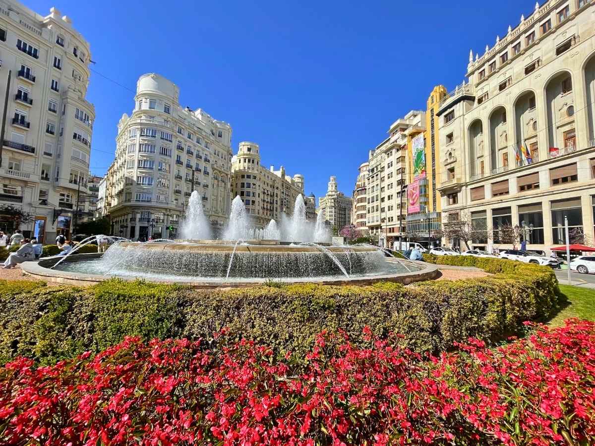 A fountain in Valencia Spain surrounded by historic buildings and colorful flowers