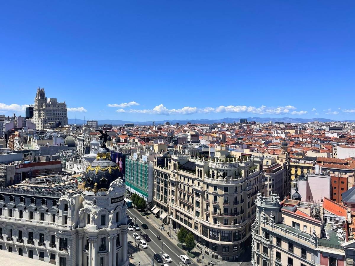 Panoramic rooftop view over Madrid with the Metropolis Building in the foreground and the Sierra mountains in the distance