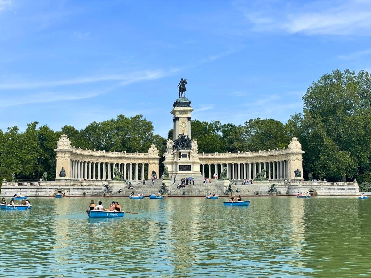 Boaters enjoying the lake in front of the grand Alfonso XII monument at El Retiro Park in Madrid