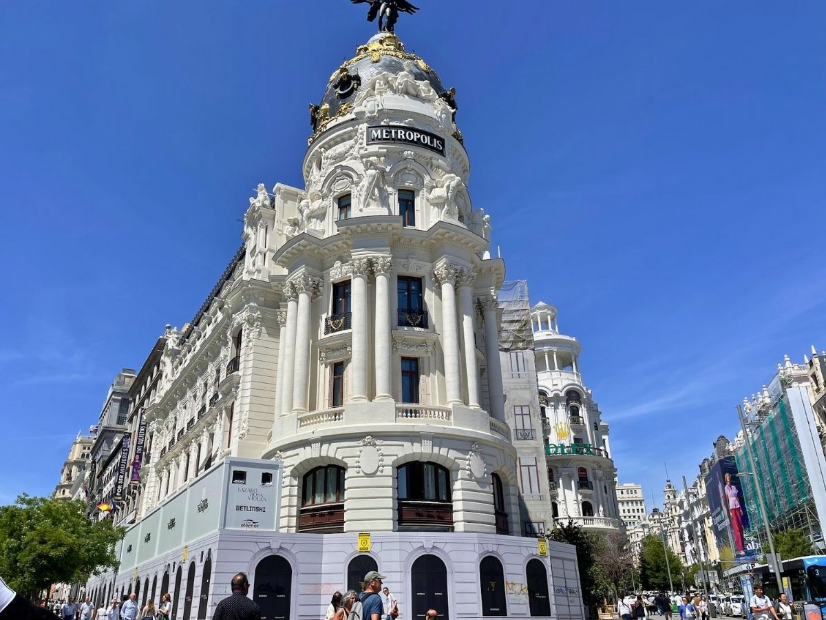 The ornate Metropolis Building in Madrid with its iconic black and gold dome, towering above the busy Gran Vía