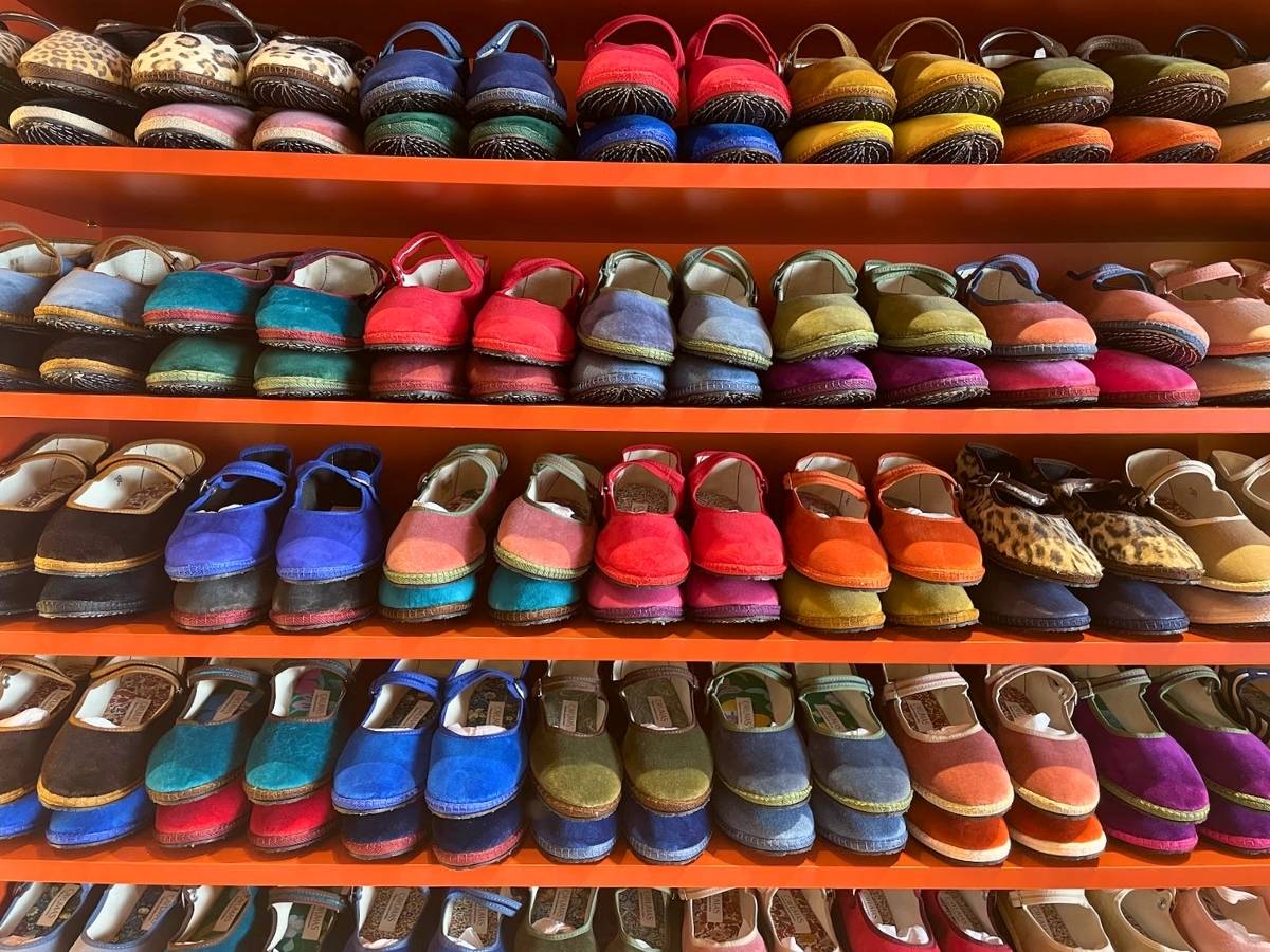 Colorful velvet espadrilles displayed on shelves inside Cayumas in Madrid