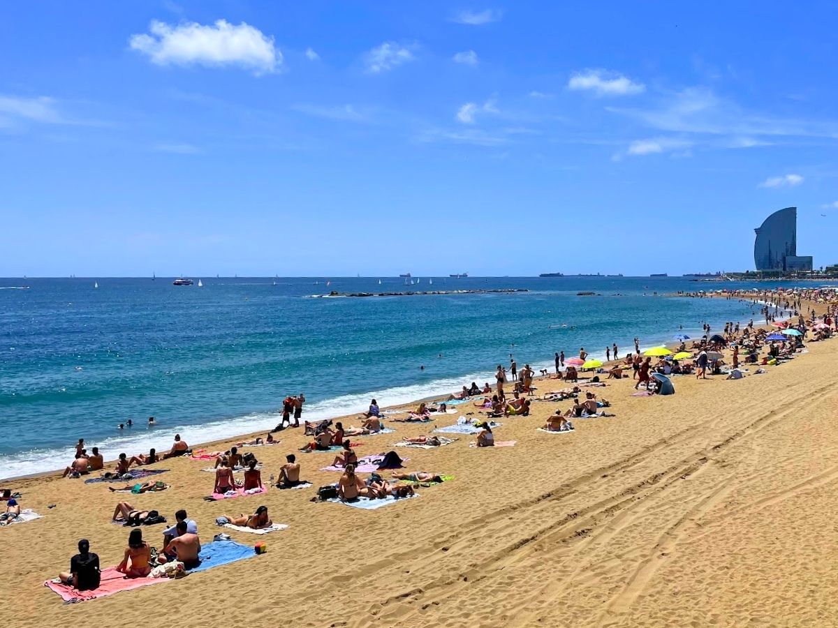 Sunbathers relax along the golden sand shoreline of Barceloneta Beach in Barcelona