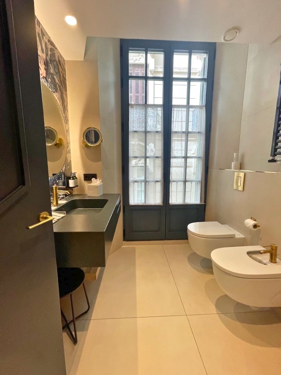Bathroom at Hotel Catalonia Puerta del Mar with modern fixtures, a large window, and gold-accented sink and mirrors