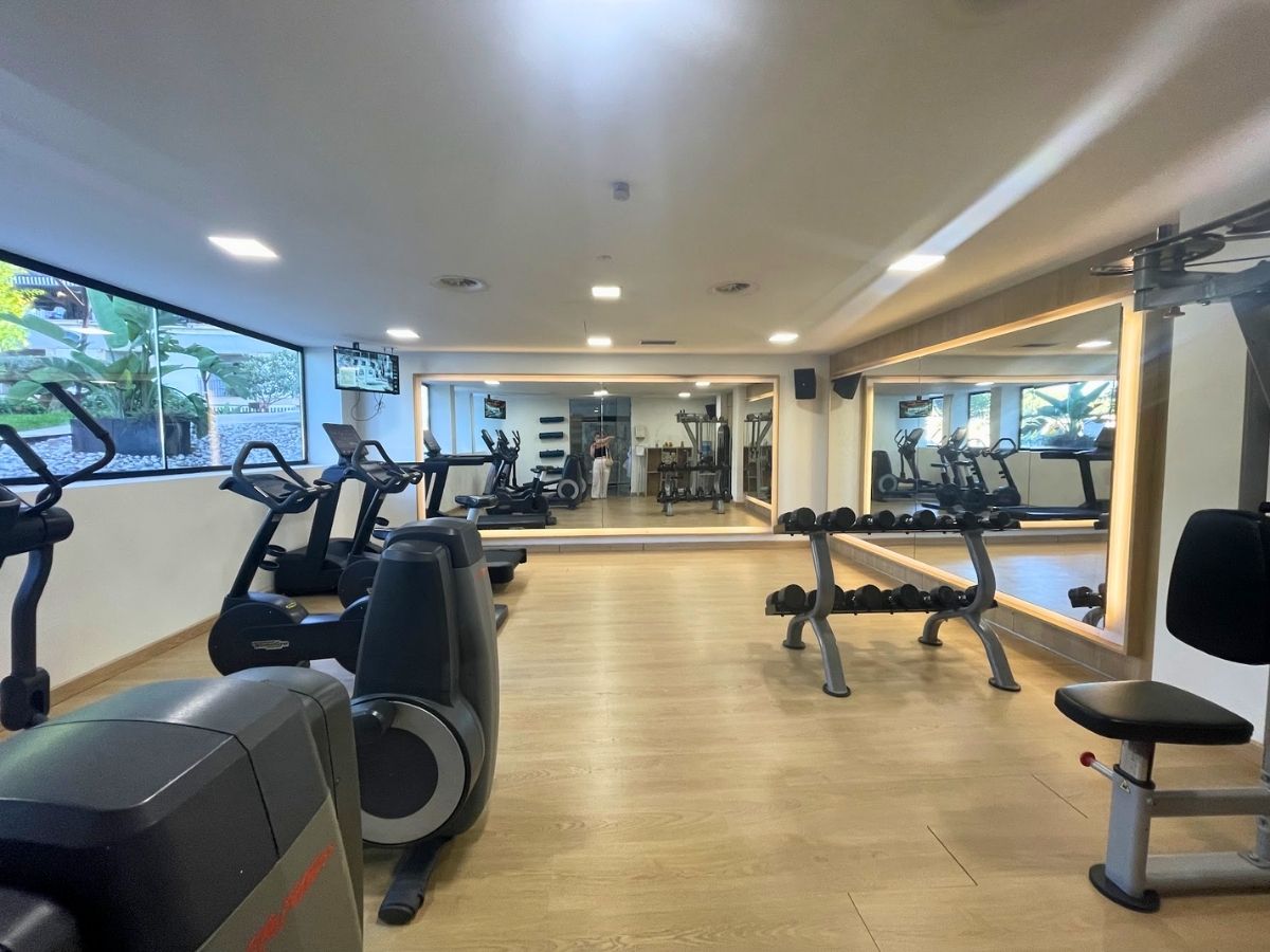 Fitness center at Secrets Mallorca Villamil equipped with cardio machines, free weights, and wall mirrors