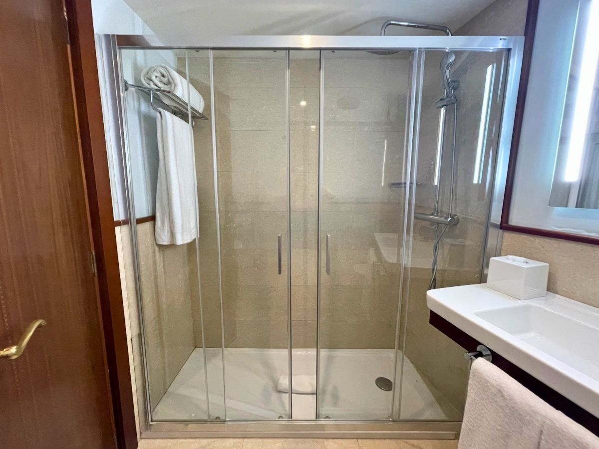 Glass-enclosed shower in a well-lit bathroom at Secrets Mallorca Villamil with towels hanging on a rail