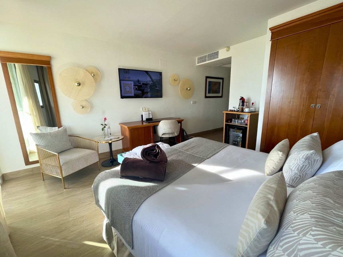 Interior view of a cozy room at Secrets Mallorca Villamil with a flat-screen TV, sitting area, and minibar