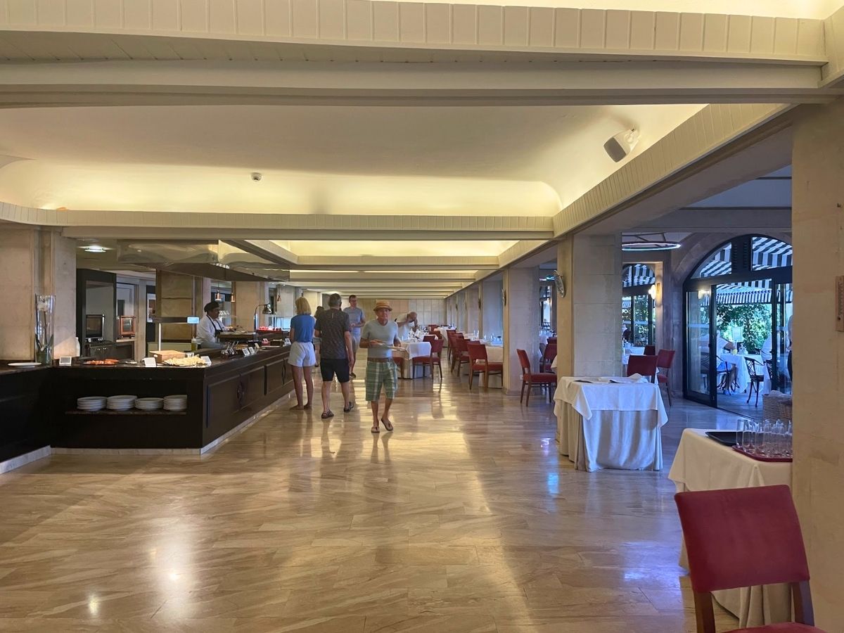 Buffet dining area at Secrets Mallorca Villamil with red chairs, multiple food stations, and natural lighting