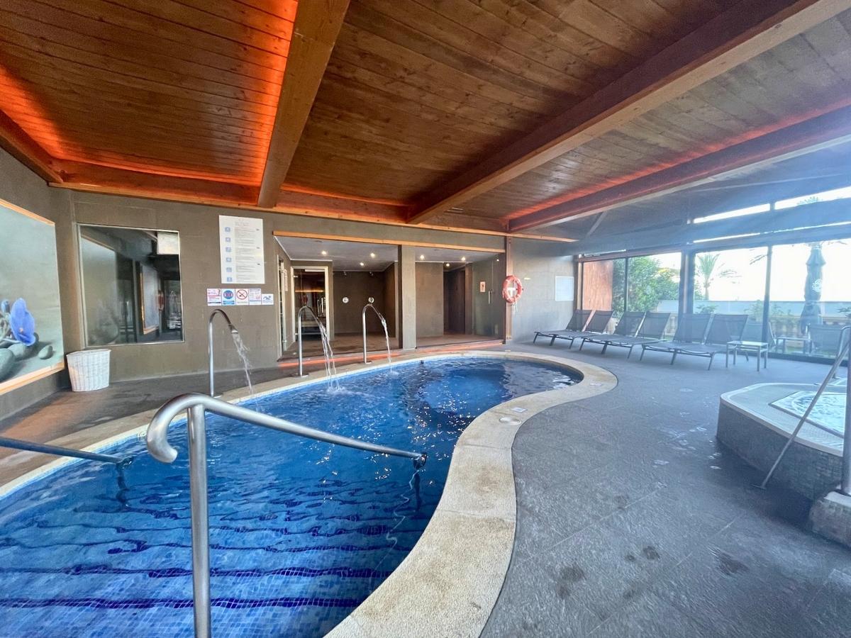 Indoor spa pool at Secrets Mallorca Villamil with water jets, wooden ceiling, and lounge chairs