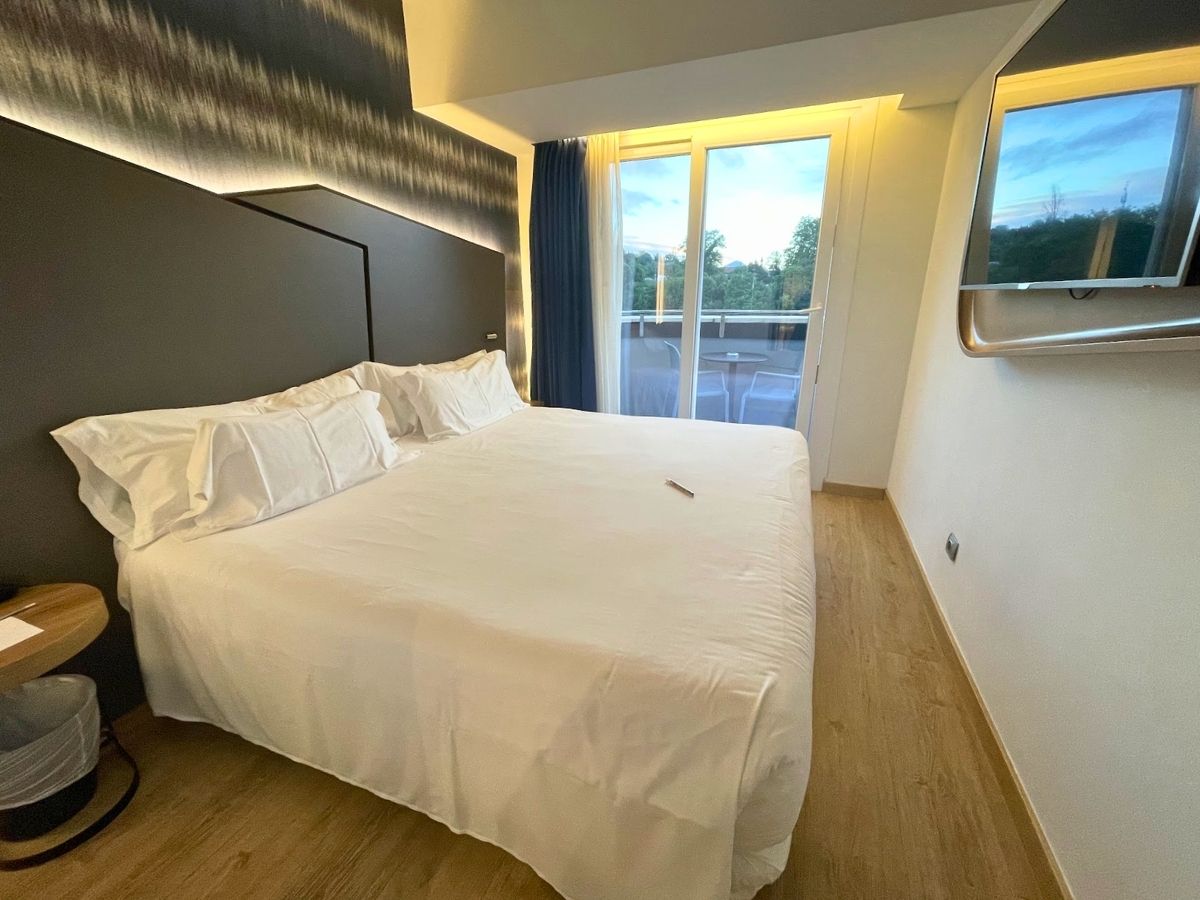 Modern hotel room at Barcelo Costa Vasca with a large white bed and balcony doors overlooking greenery in San Sebastian