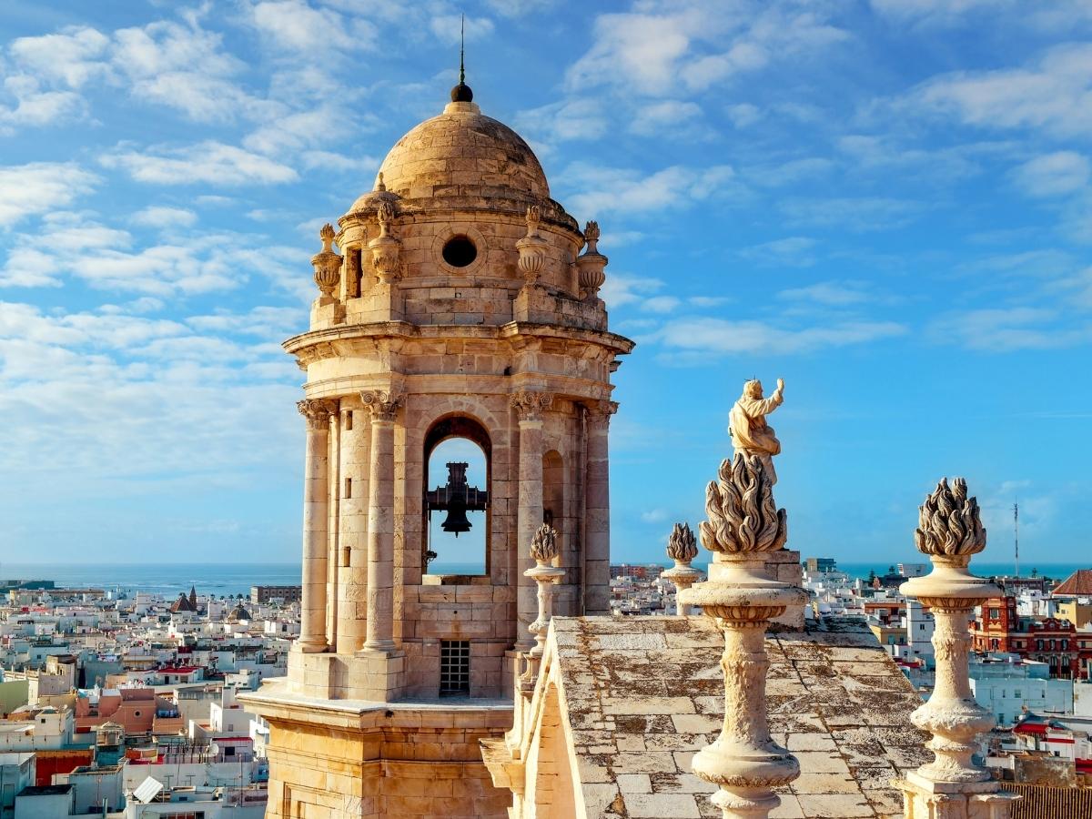 Close-up of the Cádiz Cathedral bell tower with statues and panoramic views of the city and sea