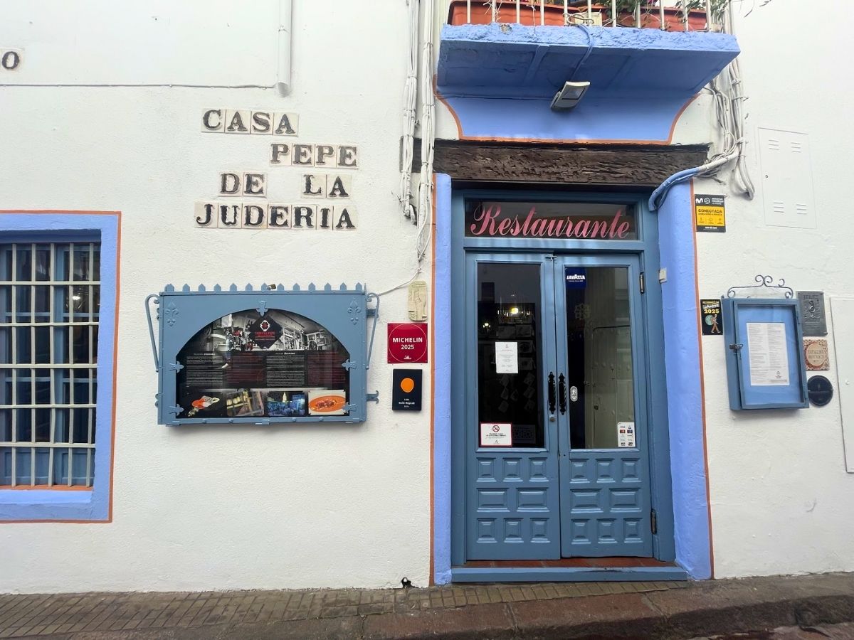 Facade of Casa Pepe de la Juderia restaurant in Cordoba Spain with blue doors signage and awards displayed on the wall