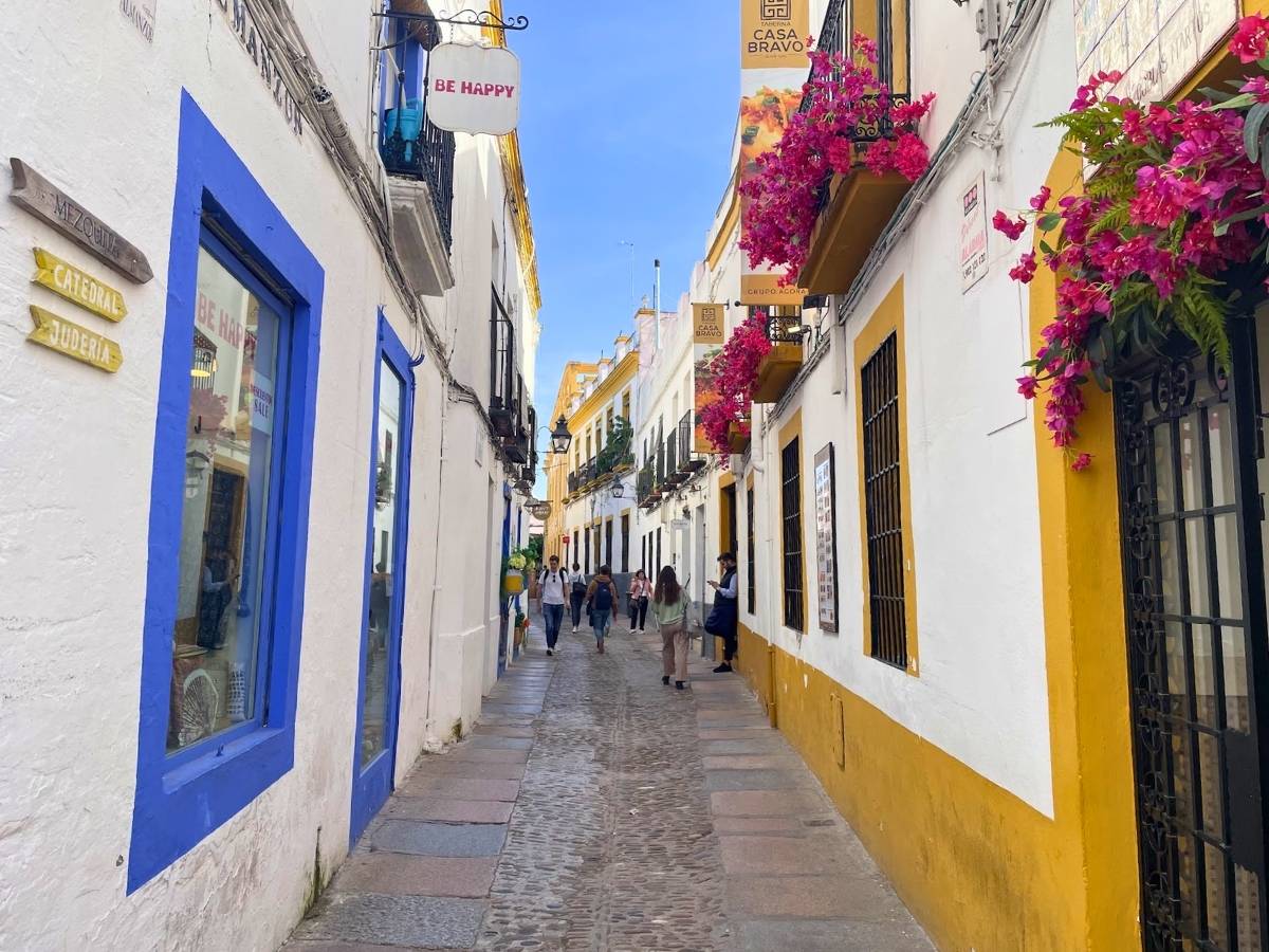 Charming narrow street in Cordoba Spain with whitewashed buildings bright flower boxes and pedestrians walking along cobblestones