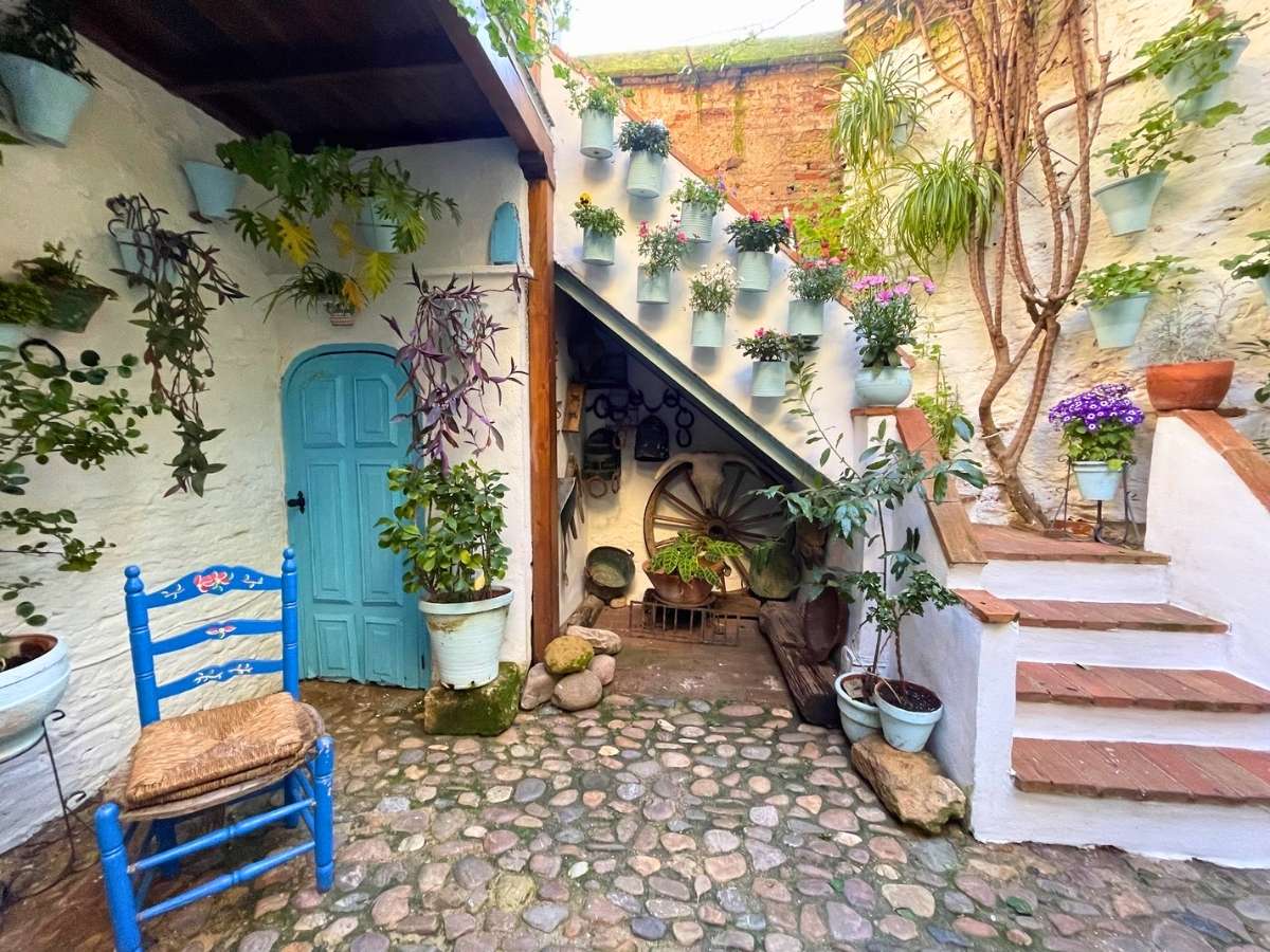 Traditional Cordoba Spain courtyard with cobblestone floor blue door potted plants and rustic staircase