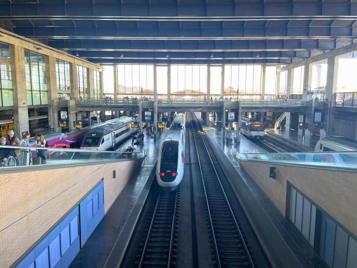 Train station in Cordoba Spain with modern high speed trains on multiple tracks inside a large open terminal building