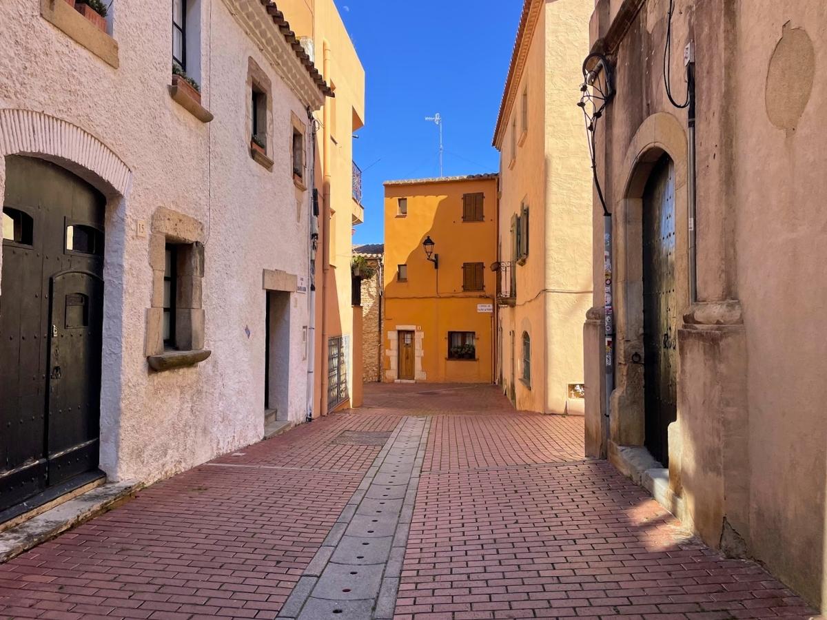 Narrow alley in Begur Spain framed by pastel colored buildings and cobblestone path