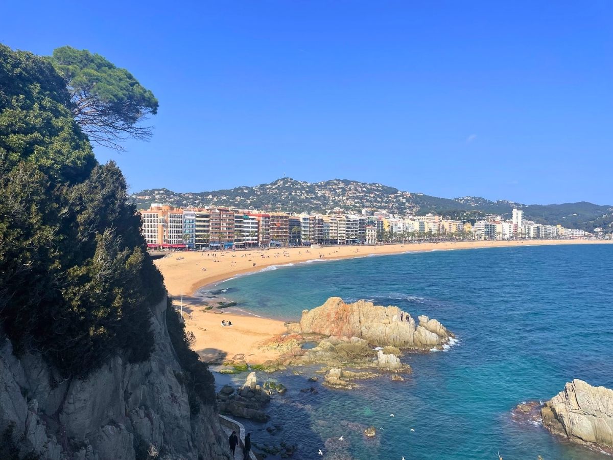 View of Lloret de Mar beachfront skyline and bay from a rocky coastal lookout along the Camí de Ronda