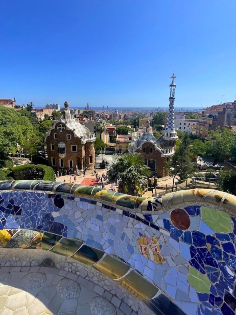 View of the colorful mosaic terrace and entrance buildings at Park Güell overlooking the city of Barcelona