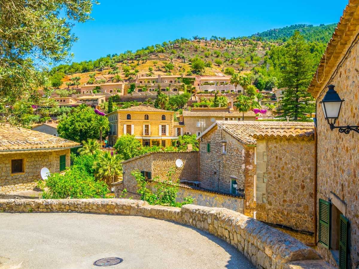 Traditional Mallorca hillside village of Deia with stone homes and lush greenery under a clear sky