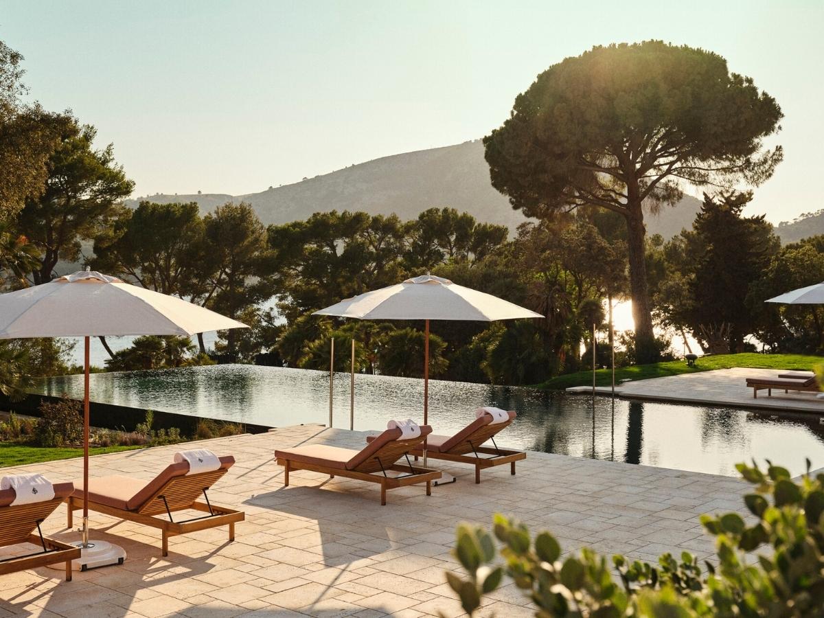 Luxury pool terrace at Four Seasons Mallorca at Formentor surrounded by pine trees and mountains overlooking the sea at sunset
