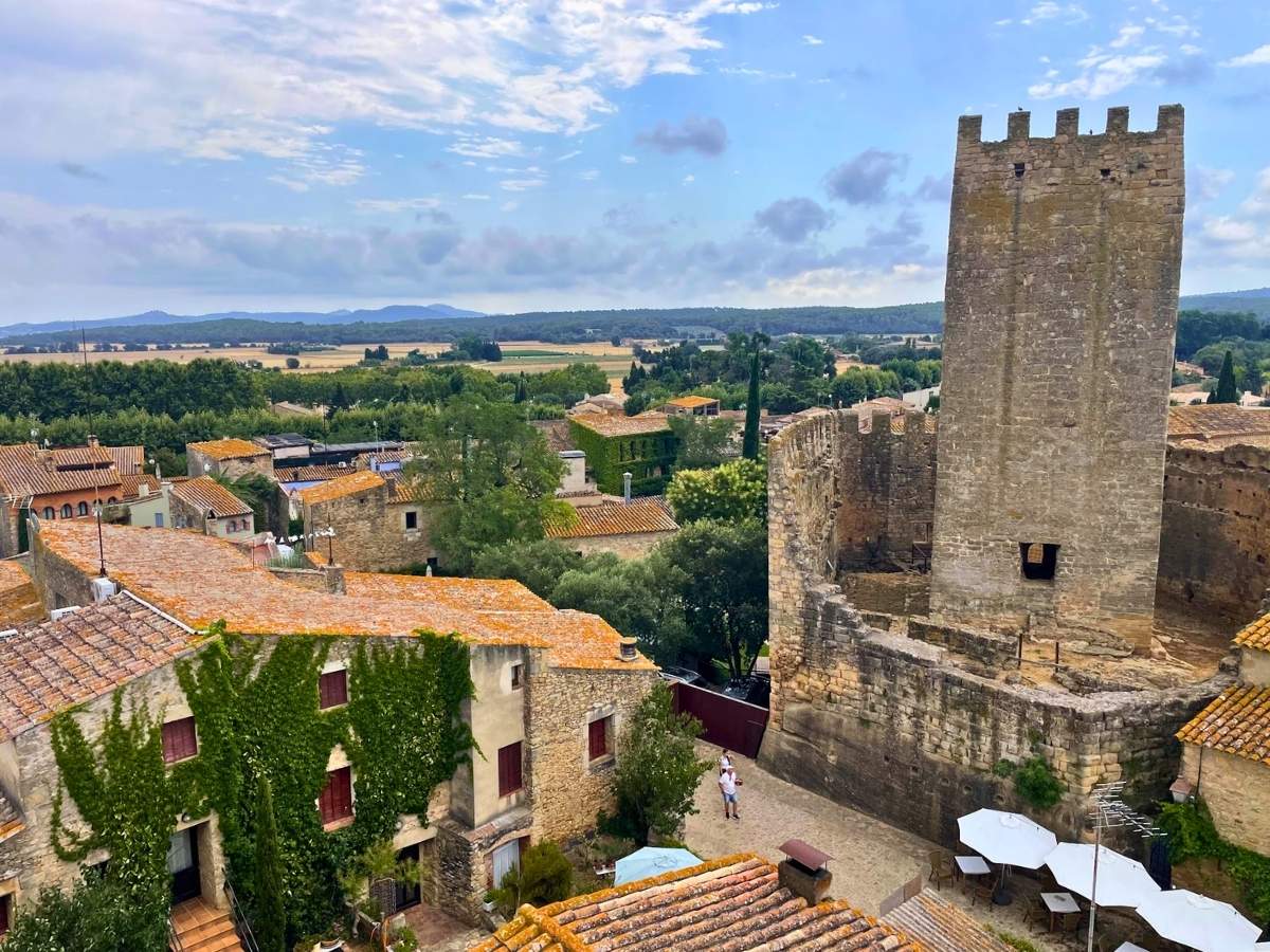 View across Peratallada featuring a medieval stone tower, historic rooftops, and the surrounding Catalan countryside