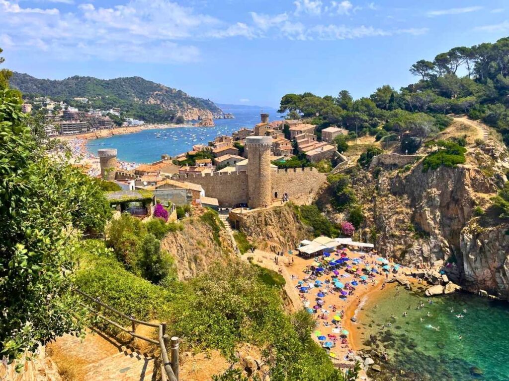 Panoramic view of Tossa de Mar with its medieval castle overlooking a secluded beach and turquoise Mediterranean water