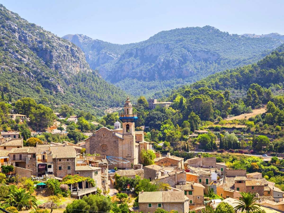 Mountain village of Valldemossa nestled among green hills with stone houses and a church tower