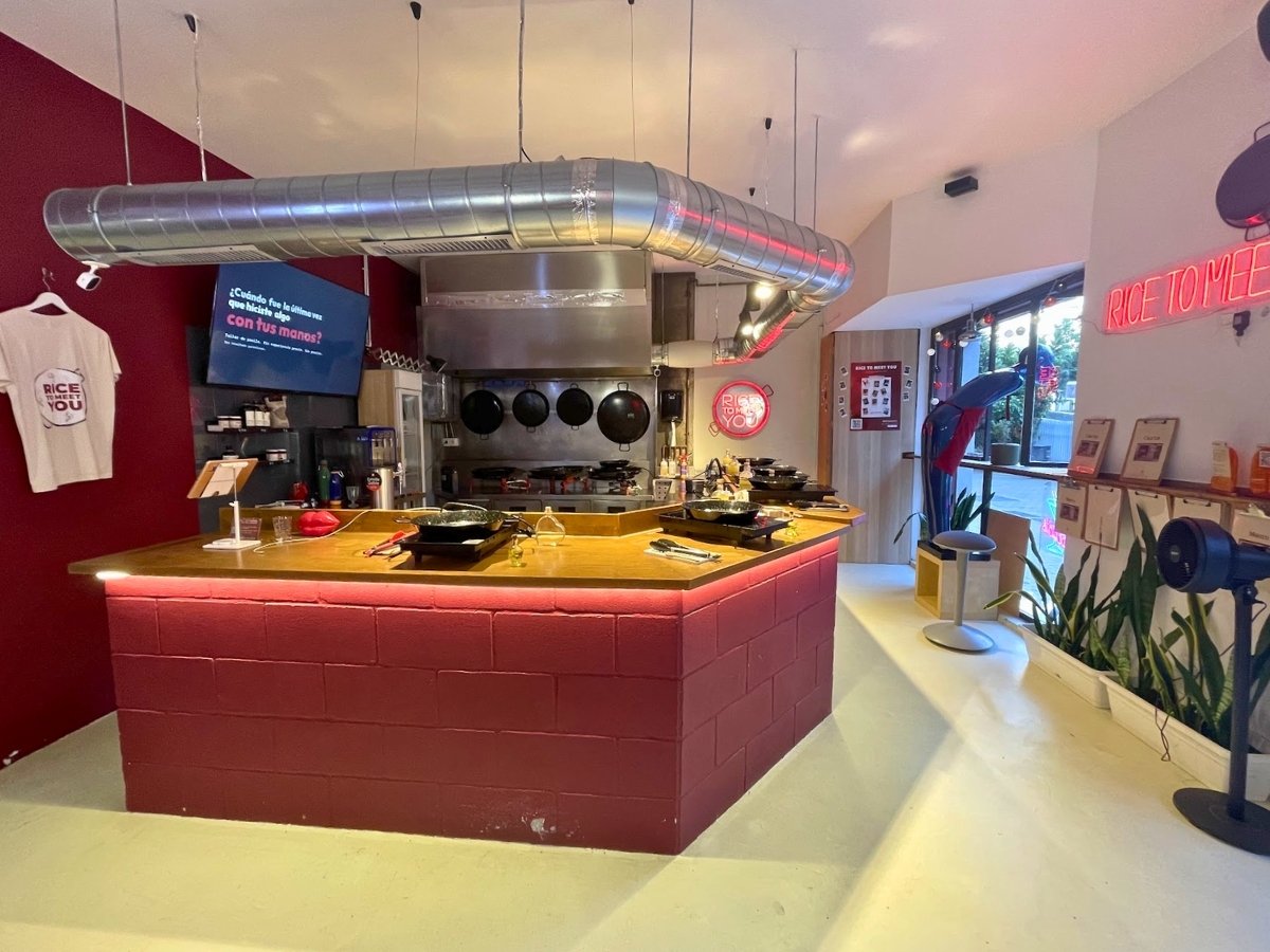 Modern Rice to Meet You cooking space with individual paella stations and neon signs