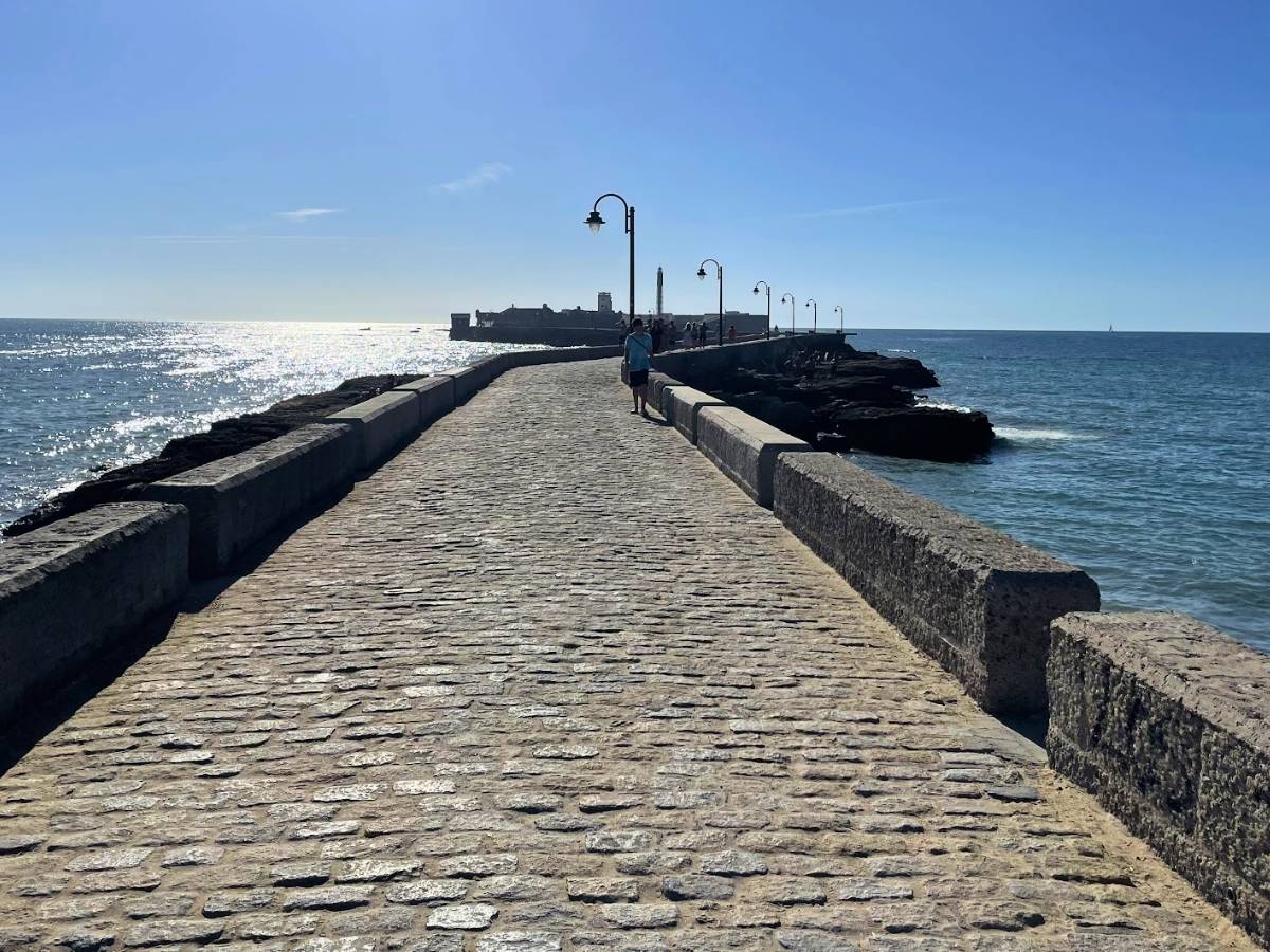 Stone walkway over the Atlantic Ocean leading toward Castillo de San Sebastián in Cádiz