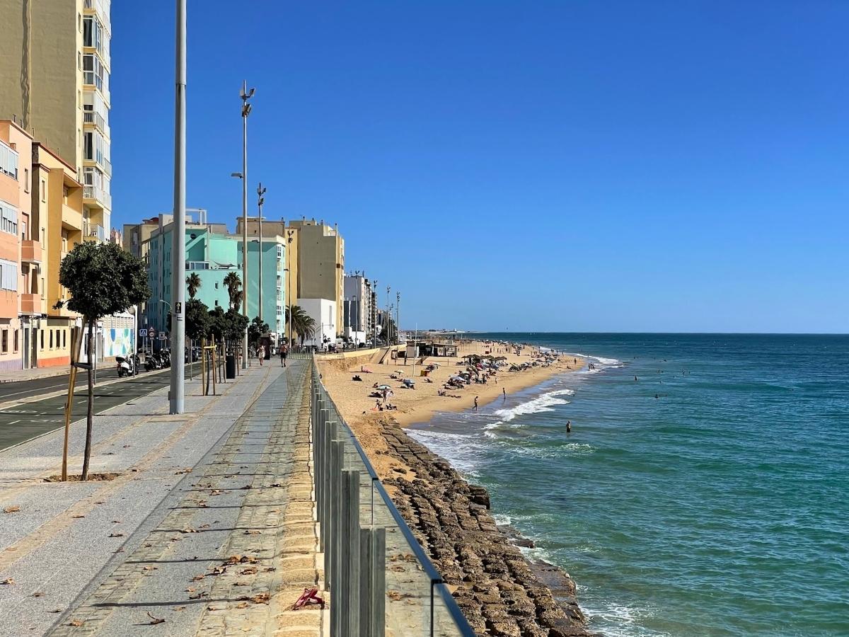 Playa de la Victoria with a beachfront promenade and apartment buildings along the coast in Cádiz