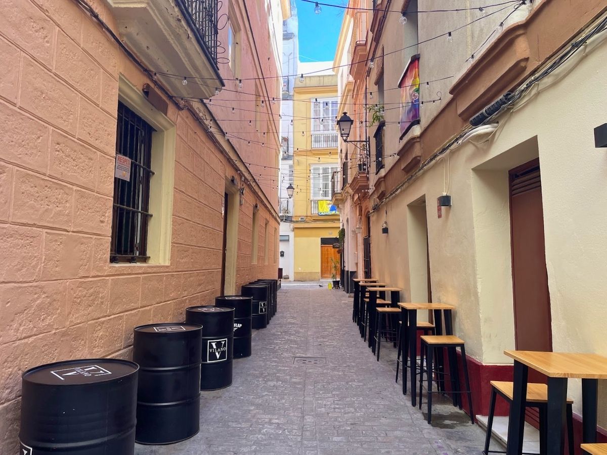 Narrow street in El Pópulo lined with colorful buildings, outdoor tables, and string lights