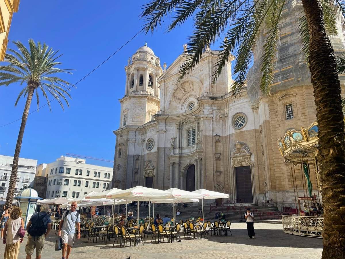 Cádiz Cathedral framed by palm trees and outdoor cafe seating