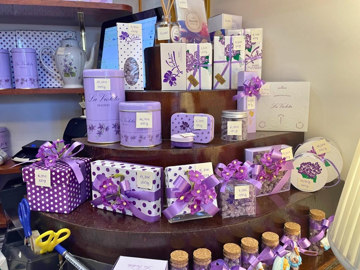 Purple tins, boxes, and bags of traditional violet sweets on display inside La Violeta in Madrid