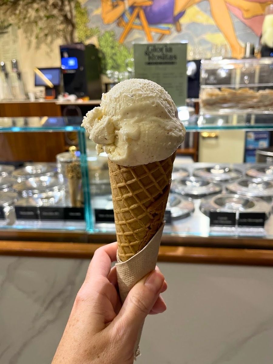 Scoop of vanilla and cinnamon ice cream in a waffle cone at an ice cream shop in Seville